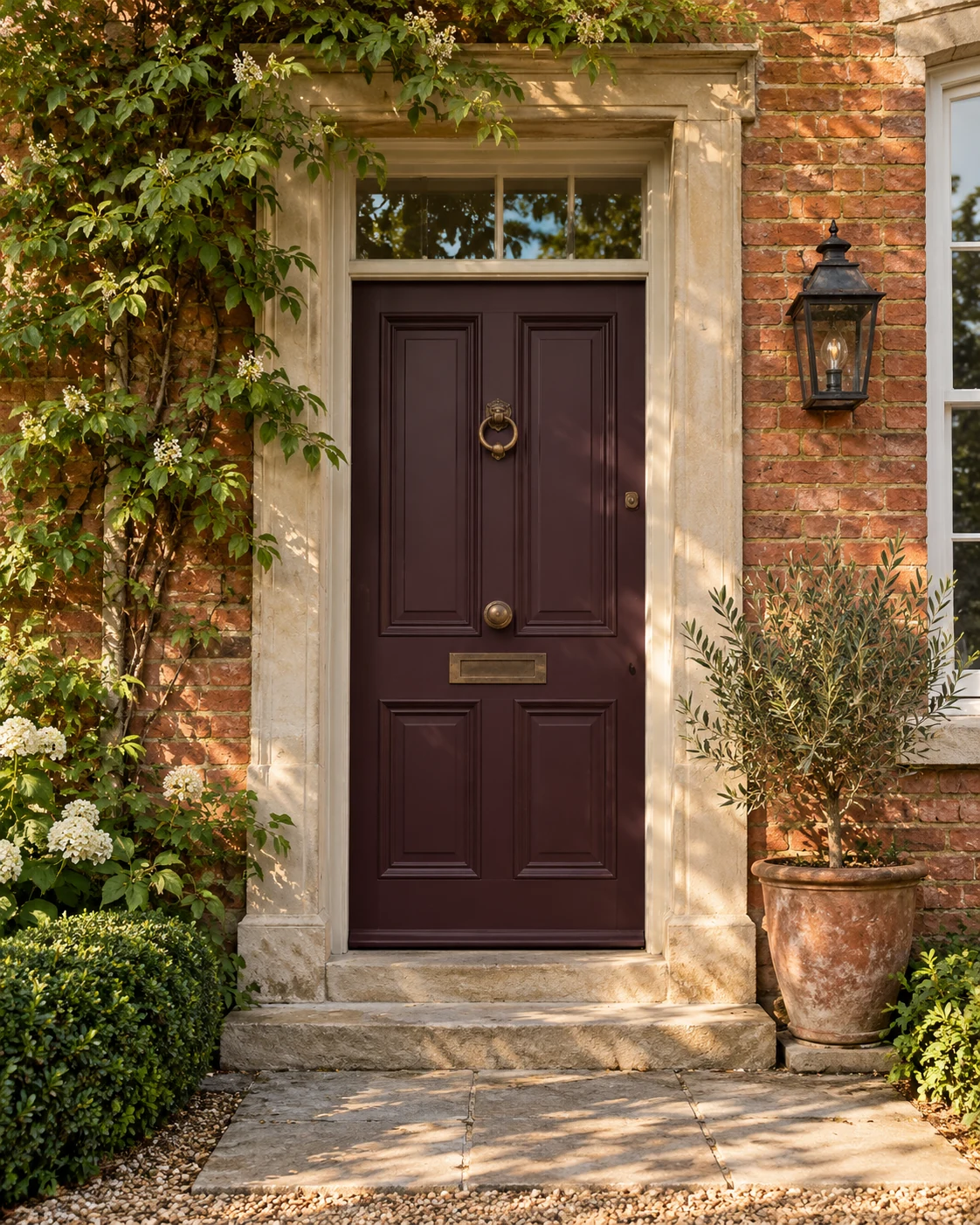 An aubergine front door with bronze fittings and warm brickwork